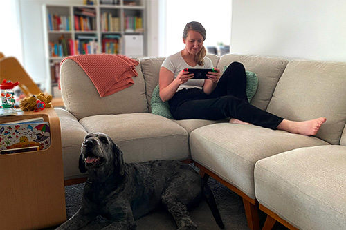 Lady relaxing on the couch playing a video game, with her dog in the foreground. Lady relaxing on the couch playing a video game, with her dog in the foreground.